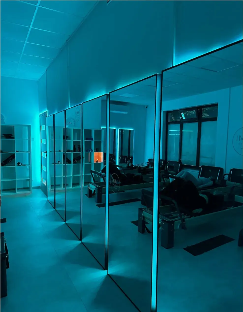 Studio Lumi Pilates w Wołominie – sala z reformerami i lustrami w turkusowym świetle
